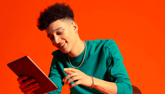 Junger Mann, der auf ein Tablet schaut und lächelt